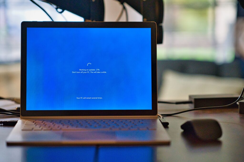 Photo of a laptop displaying a blue Windows "upgrade in progress" screen