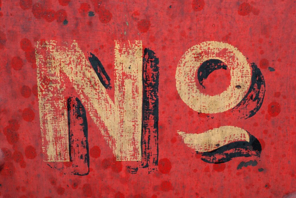 A faded gold "NO" painted on a red background.
